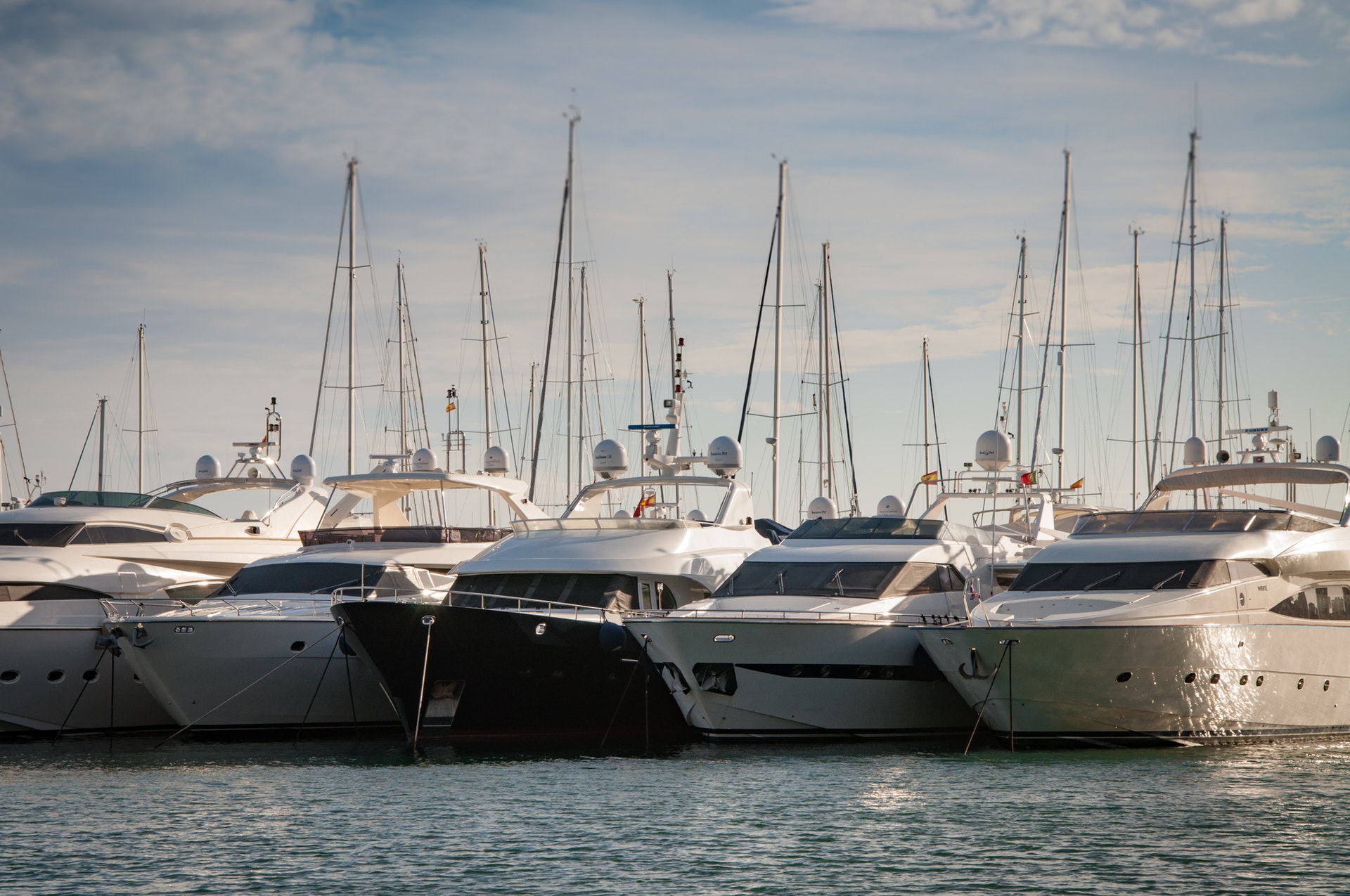 large boats and yachts side by side in a protected harbor marina