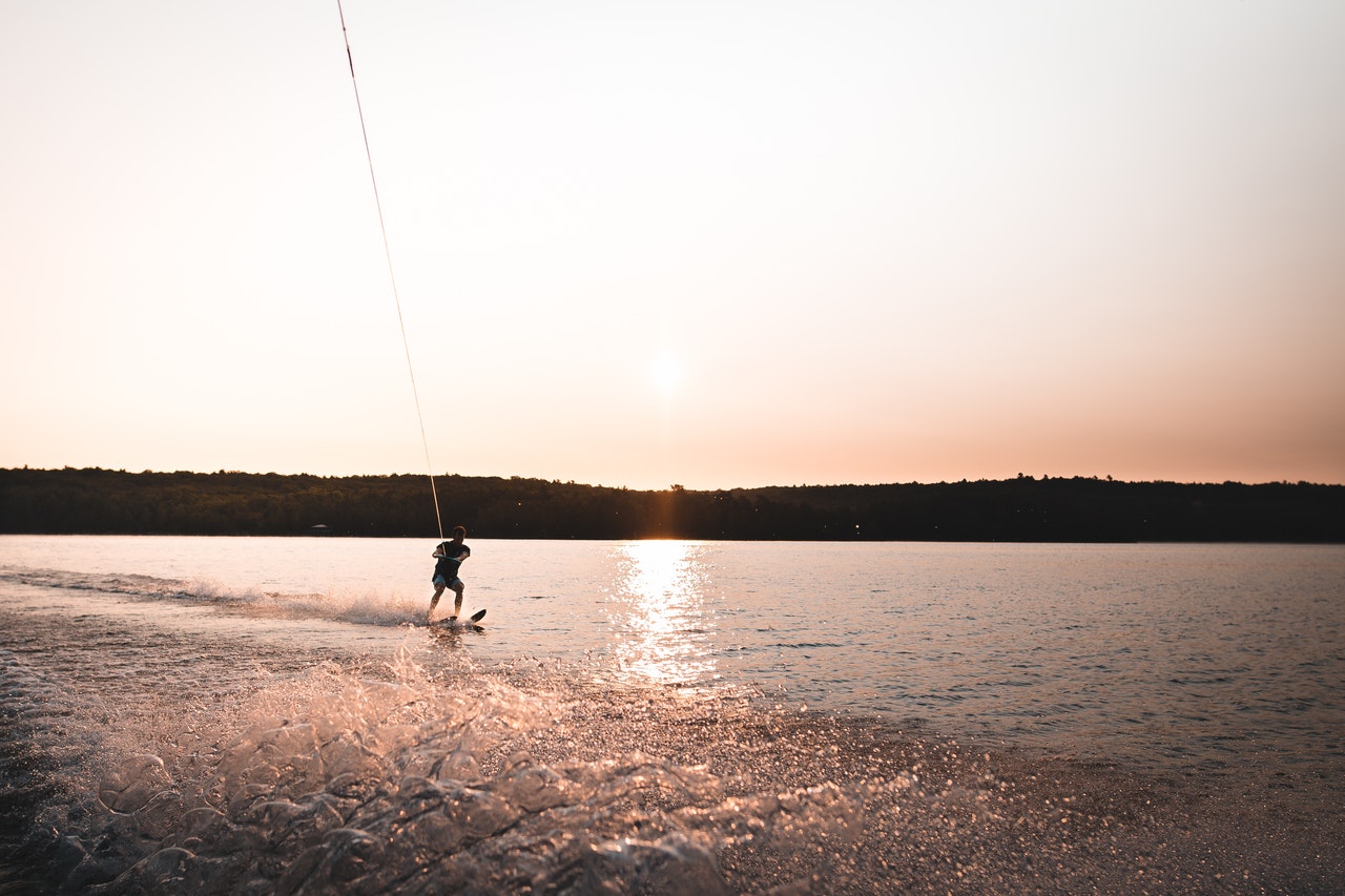 best tow rope being held by man on water ski with sunset in background